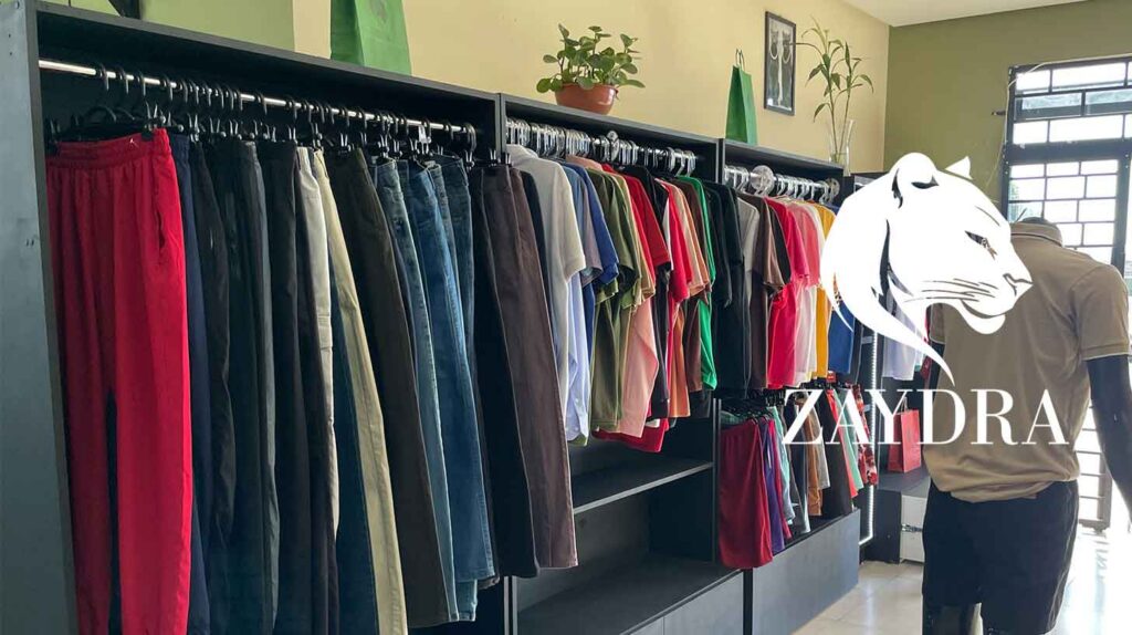 Zaydra: loja de roupas, com araras de calças e camisetas e manequim com camisa polo.